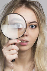 Young woman looking through a magnifying glass