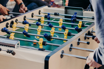 Friends play table football game, spend free time in entertainment center. Recreation and leisure...
