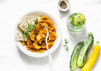 Tomato sauce zucchini stew on a light background, top view. Vegetarian lunch