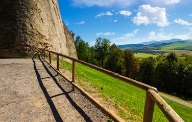 Fototapeta na wymiar castle wall and railing on a hill. view in to the beautiful mountainous landscape 