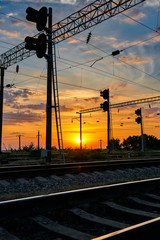 Fototapeta na wymiar railroad infrastructure during beautiful sunset and colorful sky, railcar and traffic lights, transportation and industrial concept