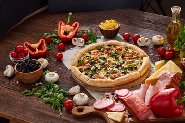 Pizza still life. Freshly baked pizza and its components arranged on wooden background.