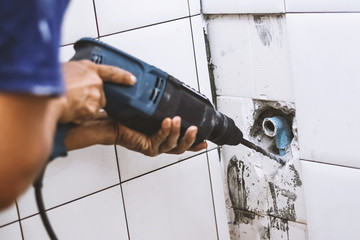plumber drilling water pipe in toilet