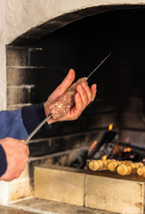 Man string a meat on a skewer to cooking a very delicious kebab. Summer day. Family dinner.