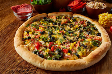 Pizza still life. Part of freshly baked pizza and its components arranged on wooden background.