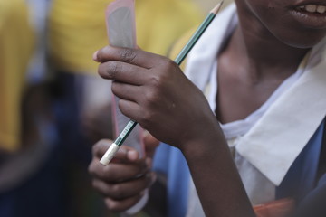 african education close up - macro photography of a black african school kid hand holding a pencil, outdoors  in the Gambia, Africa on a summer day