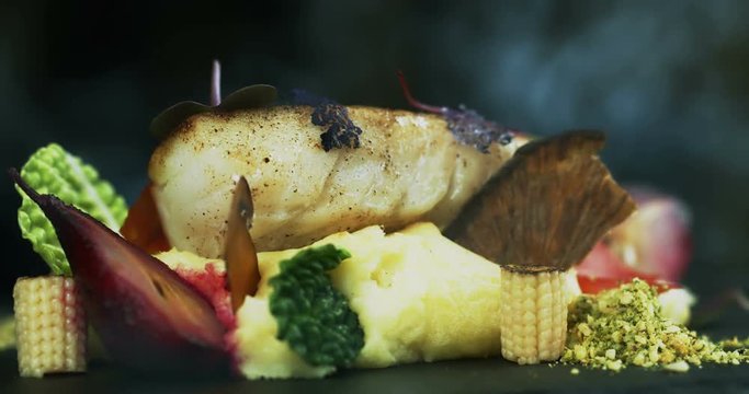 Professional chef in a modern restaurant is preparing cod fillet