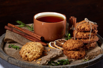 Christmas teatime with oatmeal, chocolate biscuits, and spices, on wooden background, close-up, selective focus.