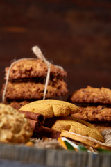 Fototapeta na wymiar Conceptual composition with assortment of cookies and cinnamon with napkin on a wooden barrel, selective focus