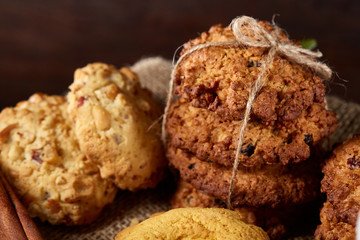 Conceptual composition with assortment of cookies and cinnamon with napkin on a wooden barrel, selective focus