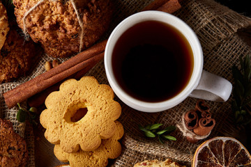 Cookies with cinnamon and two cups of tea on a burlap napkin, selective focus, close-up, top view.