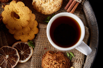 Traditional Christmas tea concept with a cup of hot tea, cookies and decorations on a wooden background, selective focus