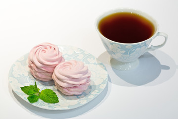 Black tea with pink blueberry marshmallow. Sweets decorated with pepper mint. Tea time.