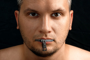 A man's mouth is closed with a zipper from his clothes. Photoshop. Black background. The concept of...