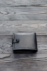 Black leather elegance men's wallet on dark wooden background. Vertical.
