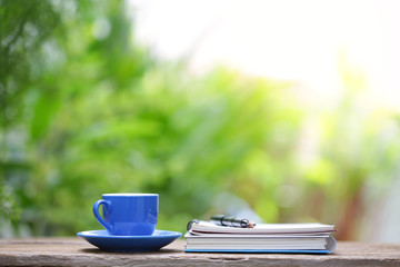 Blue cup and notebook on wooden table at outdoor