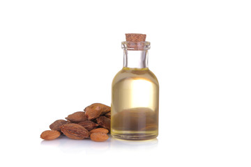 Apricot seed oil in a glass bottle next to apricot bones on a white isolated background