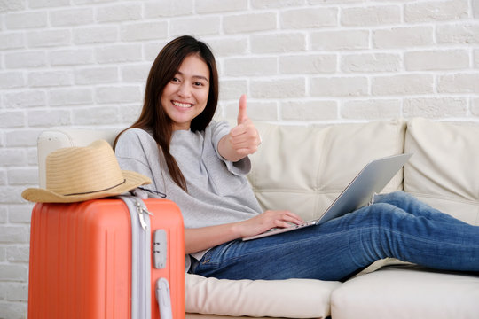 Young asian woman traveler using laptop and smiling with ok guster hand sign, blogger, travel summer holiday vacation concept