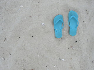 Fototapeta na wymiar Blue flip flops in the sand at the beach 