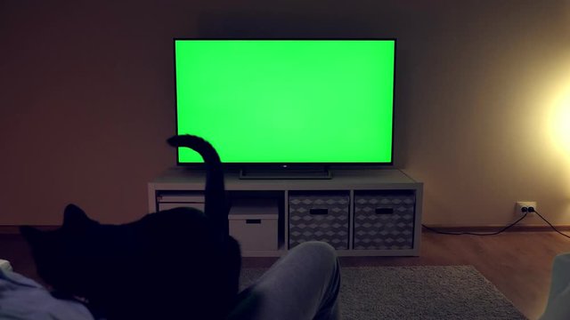 Watching tv with green screen at home interior. Evening