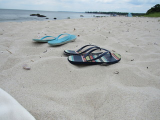 Two pairs of flip flops in the sand on the beach 
