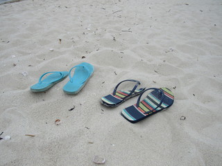 Two pairs of flip flops in the sand on the beach 
