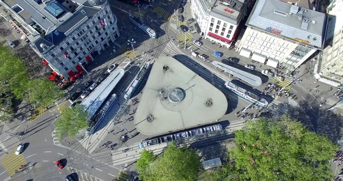 Drone shot slowly flying up and away from Bellevue place in Zurich to reveal the city behind it.