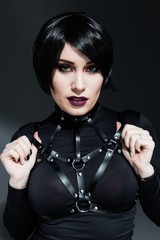 Portrait of sensual young woman with bright makeup wearing harness belts