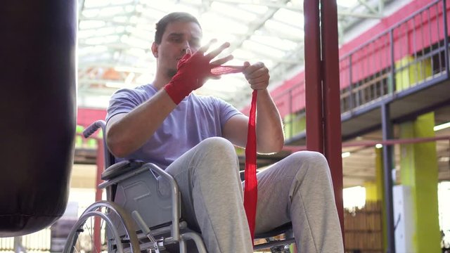 Portrait man with a disability in a wheelchair wound boxing tapes on his hands