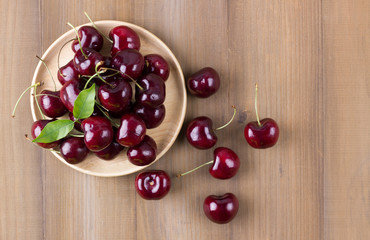 Fresh cherry in wooden plate on wooden background