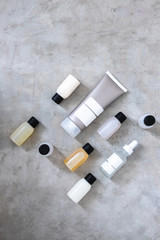 Bottles and tubes with salon cosmetic products from above on concrete table. Skincare,  moisturizers, treatments, essences, body and hair oils. Minimalism beauty blogging concept.