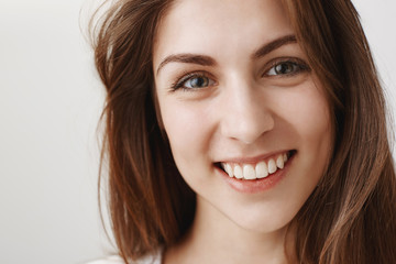 Close-up studio shot of beautiful caucasian brunette smiling broadly and looking with confidence...