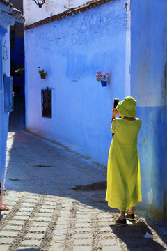 Unrecognizable tourist woman making photos in the streets of the Medina of Chefchaouen, Morocco