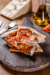 Sliced pizza with ham, cheese, mushrooms and tomato sauce on wooden cutting board. Top view.