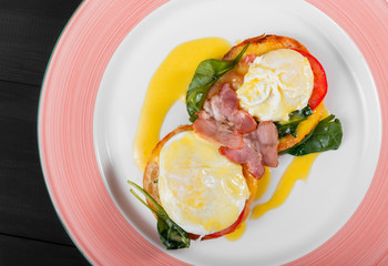 English breakfast- Fried bread toast with egg, spinach, tomatoes, mozzarella cheese and ham on plate on dark wooden background