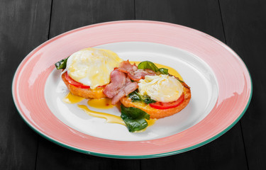 English breakfast- Fried bread toast with egg, spinach, tomatoes, mozzarella cheese and ham on plate on dark wooden background