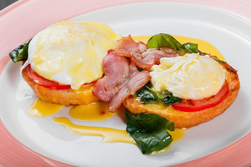 English breakfast- Fried bread toast with egg, spinach, tomatoes, mozzarella cheese and ham on plate on dark wooden background