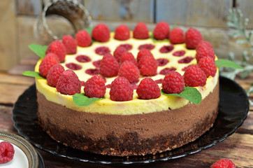 Chocolate cheesecake with raspberries on a black plate on a wooden background