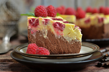 A piece of chocolate cheesecake with raspberries on a rustic plate