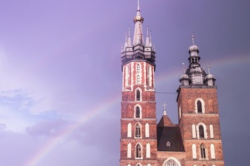 Two towers of the St Mary Basilica in Krakow against the background of a fantastic purple sky and a rainbow