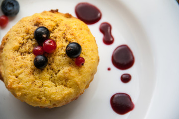 Homemade black currant cheese muffin with fresh berries and cherry sauce on white plate
