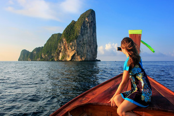 Young woman sitting in the front of a longtail boat going to Phi Phi Leh Island, Krabi Province,...