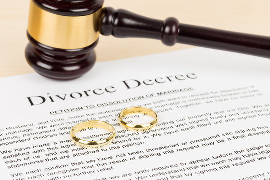 Wooden judge gavel, golden rings, and divorce decree; document is mock-up