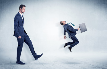 Fototapeta premium Big businessman kicking small businessman who is flying away with his briefcase on his hand 
