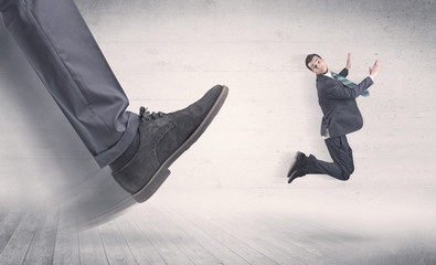 Big foot in a black shoe fire small, young, businessman who is flying away in the space
