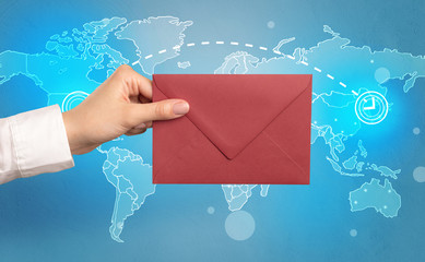 Female hand holding coloured and white envelope with blue map on the background
