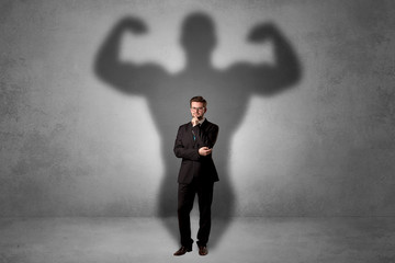 Lovely serious businessman standing with a muscular powerful shadow behind his back
