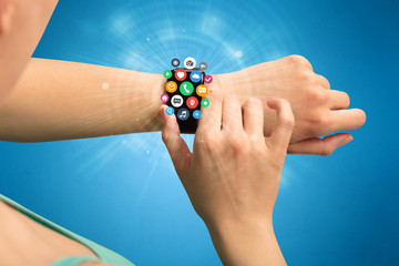 Hand with smartwatch and application symbols nearby.