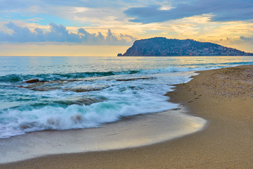 Beautiful tropical sunset on the beach of the sea with waves and foam. Alanya, Turkey.  
