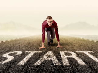 Young determined businessman kneeling at a start line 
